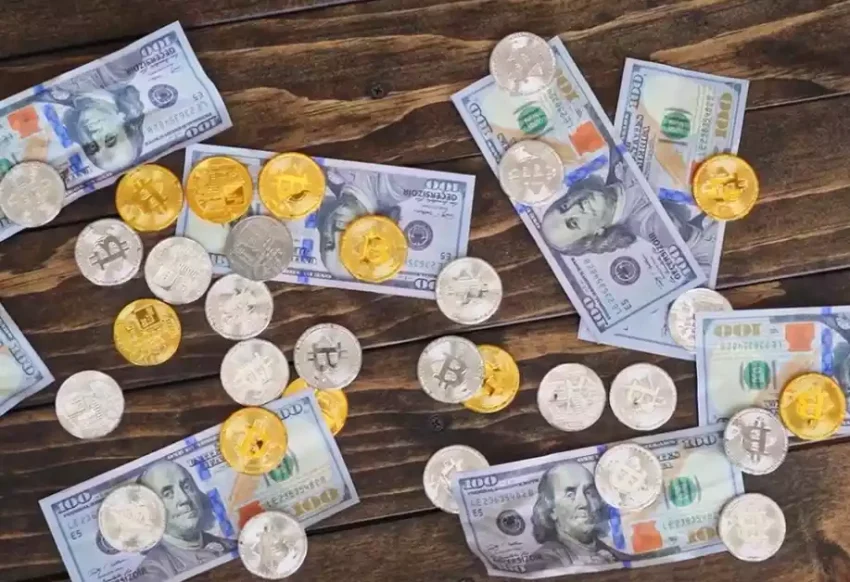Бумажные банкноты и металлические монеты со знаком криптовалюты лежат на столе и ждут криптокошелек