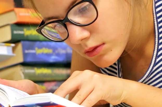 Девушка развивает свою память внимательно прочитывая книгу, чтобы запомнить все