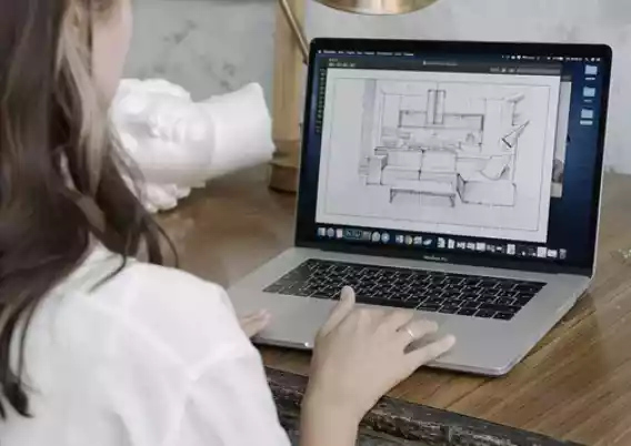 Дизайнер интерьеров продумывает дизайн кухни прорабатывая его на ноутбуке